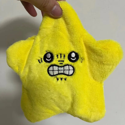 Plush yellow star toy with an embroidered silly face, held by a hand, on plain background