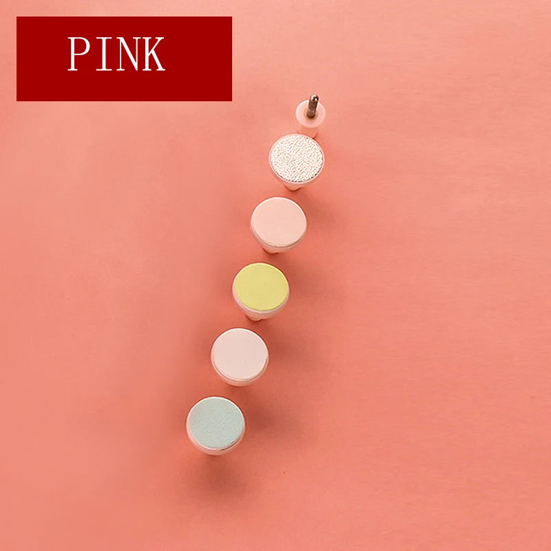 Set of five pastel pink and yellow interchangeable nail drill bits on pink background