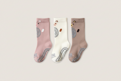 Three pairs of socks in pink, white, and brown on a light gray background